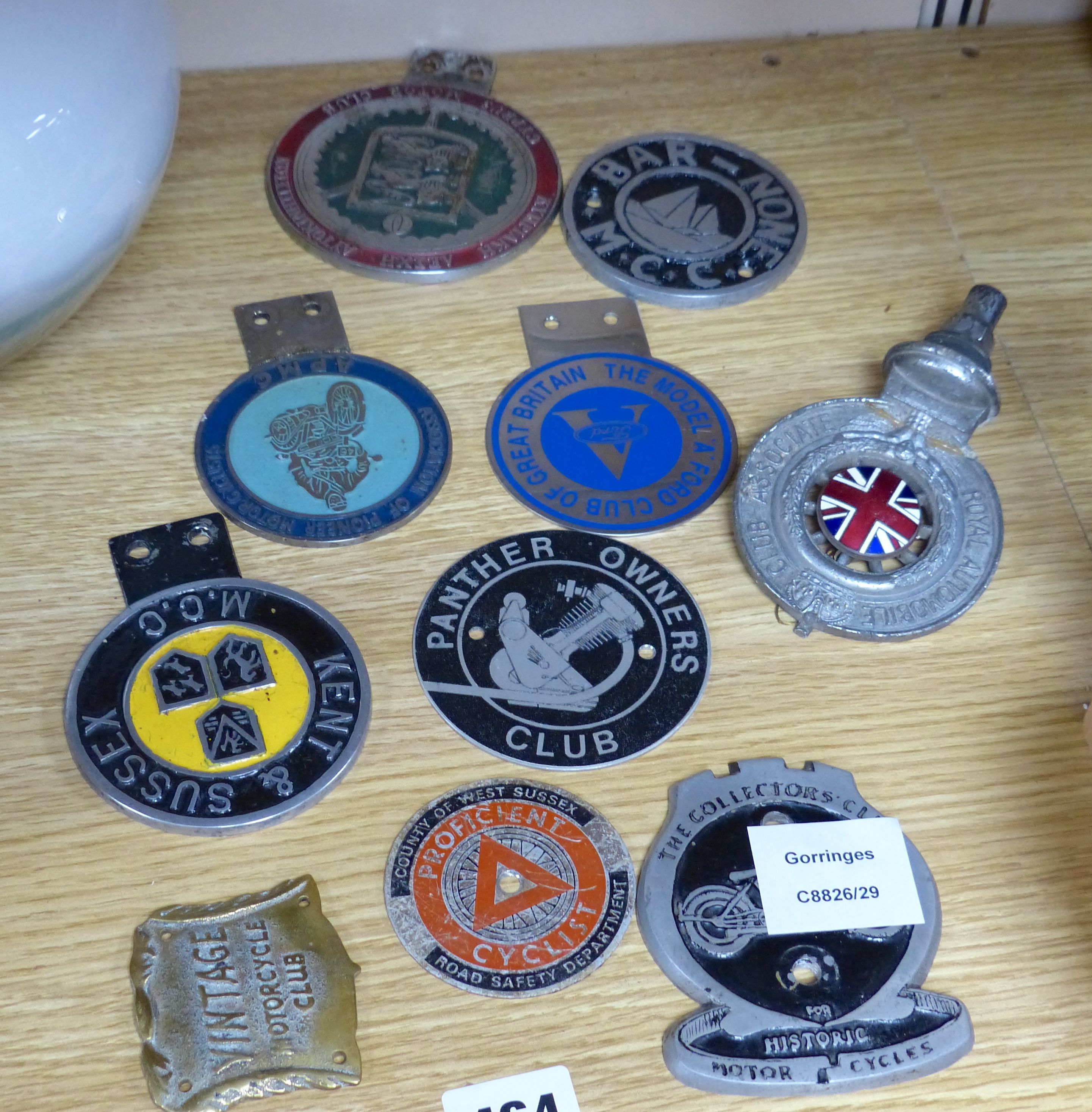 A small collection of car radiator caps and badges and motorcycle club badges